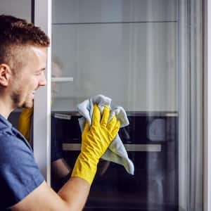 A man with rubber gloves cleaning window with cloth