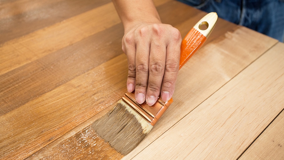 man staining wood table