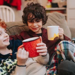 Kids sitting on sofa wrapped in blanket