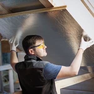 A professional placing insulation in attic