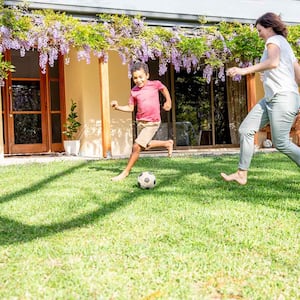 Mother and son playing soccer in the backyard 
