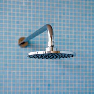 A shower head with blue tiles in the background