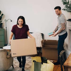 A couple unpacking boxes in living room at new home