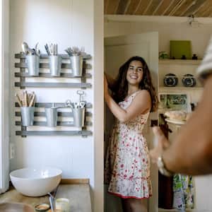 Woman in kitchen opening pantry door