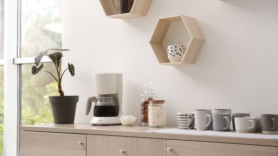 Coffee maker on console table with geometric floating shelves