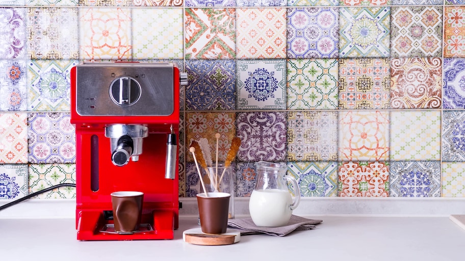 Red espresso maker in front of tile backsplash