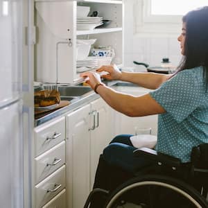 A young woman opening a kitchen cabinet