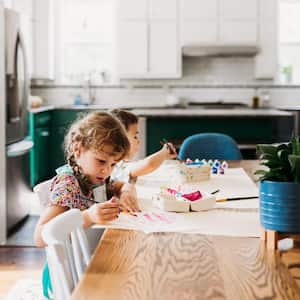 Two young kids doing arts and crafts in modern dining room
