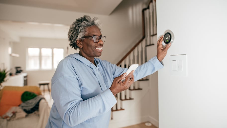 Woman adjusting wall thermostat