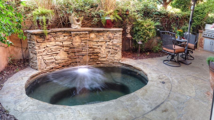 An inground hot tub with a stone waterfall feature