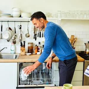 A man putting coffee mugs into dishwasher