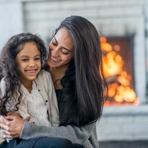 Mom and daughter sitting on the carpet in front of the fire