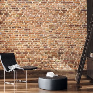 a brick wall and wood floor room with black modern reading chair and lamp, ottoman, and bookshelf with ladder