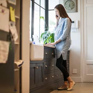 Woman talking on the phone and using laptop in the kitchen