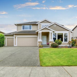 The exterior of a beige house with two garage spaces