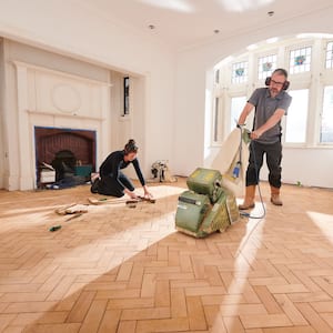 A man sanding a hardwood floor