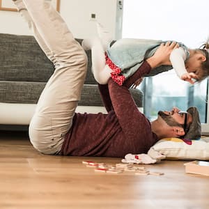 Father and daughter play on wood floor