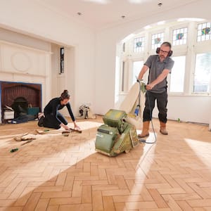 Two workers repairing a parquet floor