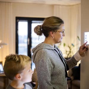 Mother using digital tablet mounted on wall at smart home