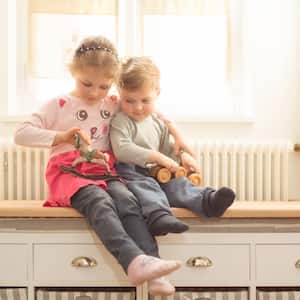 A brother and sister with wooden toys at home
