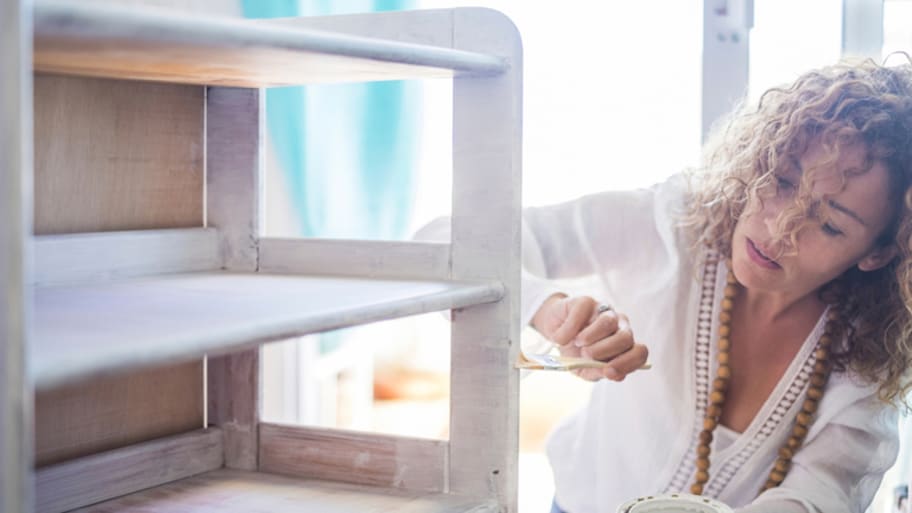 Woman painting cabinet white with chalk paint