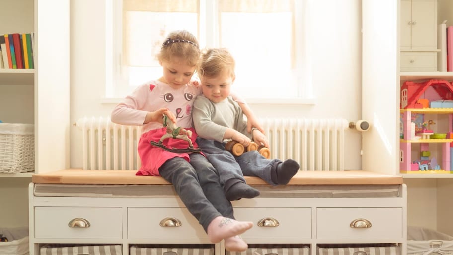 A brother and sister with wooden toys at home