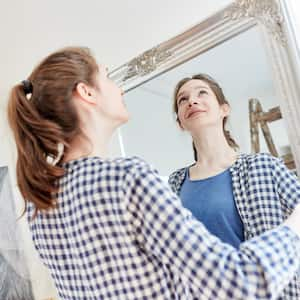 A woman getting ready to hang a heavy framed mirror on a wall