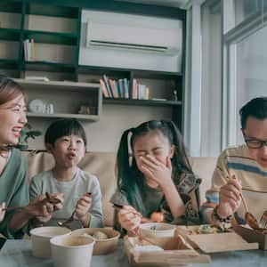 Family enjoying take out food in front of tv in living room