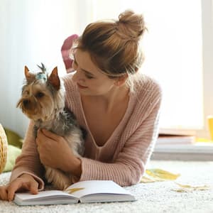 A woman with cute dog reading book at home