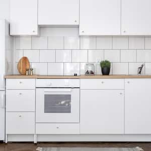 A kitchen with white cabinets and subway tiles