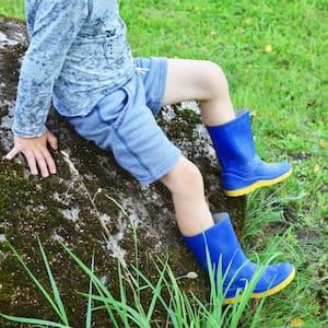 Boy sitting on a large rock in a yard