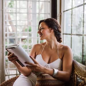 Woman reading book in sunroom and smiling