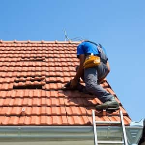 Roof repairman fixing a tile roof