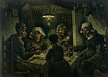 A group of five sit around a small wooden table with a large platter of food, while one person pours drinks from a kettle in a dark room with an overhead lantern.