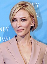 Photo of a woman smiling. She is wearing a white coat.