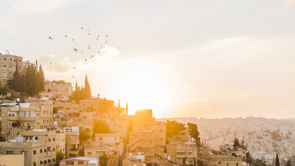 Scenic view from viewpoint of little clay houses in the hillsides of Amman city at sunset.