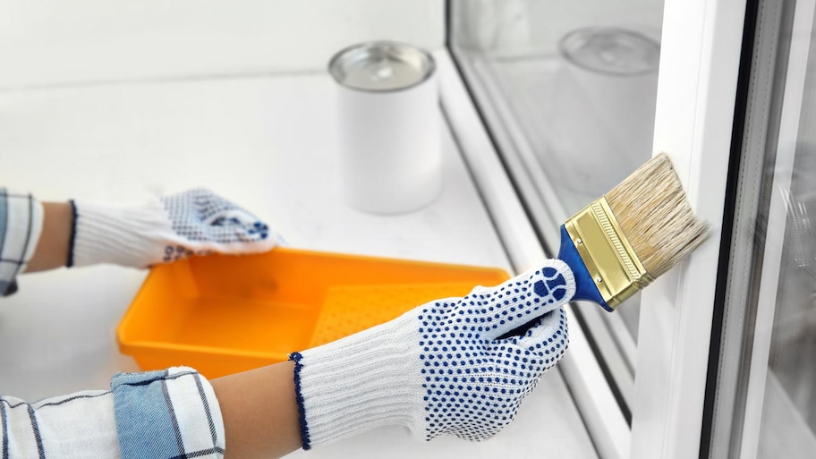 Woman painting window frame at home