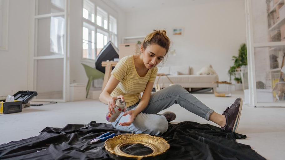 Young woman painting the old picture frame