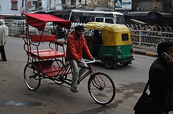 A cycle rickshaw and an auto rickshaw are seen on a street in Delhi