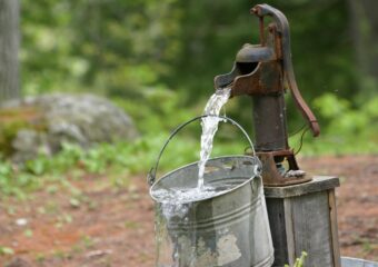 Water well pump delivering water into a pail.