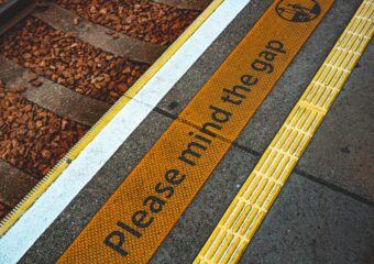 MInd the Gap warning alongside subway train rail line.