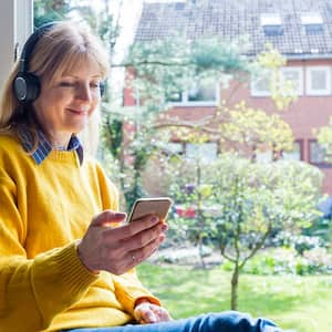 Woman wearing headphones sitting by an open window