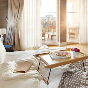 A sunlit bedroom with white draperies