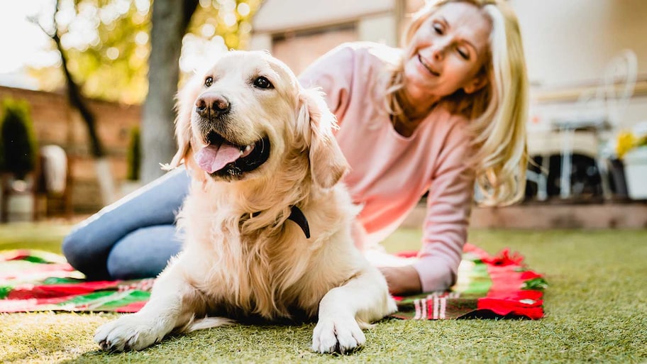 Woman and her dog on the patio sitting on a blanket 