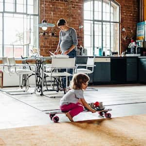 Little girl in the living room sitting on a skateboard