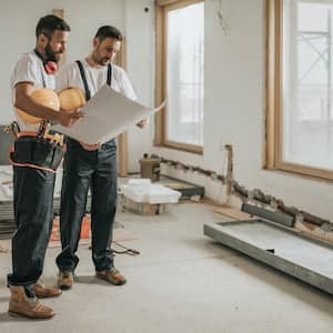 Two construction workers analyzing blueprints in the apartment