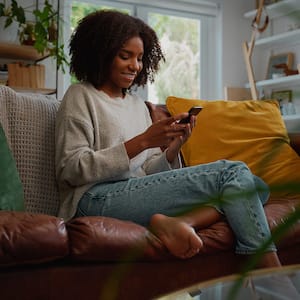 A young woman using her phone while sitting on the sofa