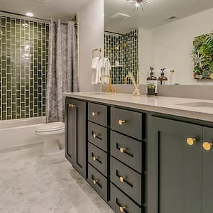 A bathroom with green tiles and brass faucets