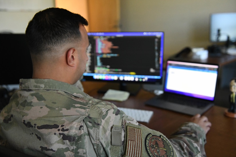 An airman sits in front of a computer