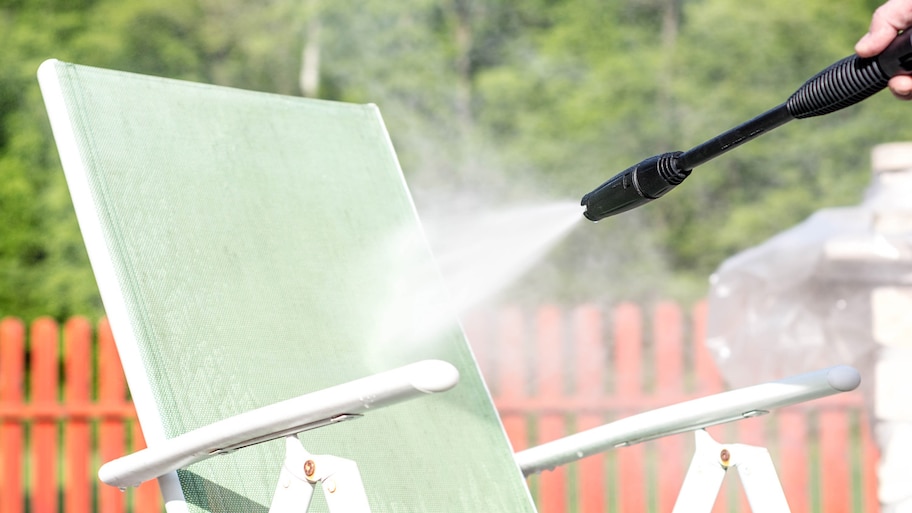 Close-up of a pressure washer cleaning garden furniture